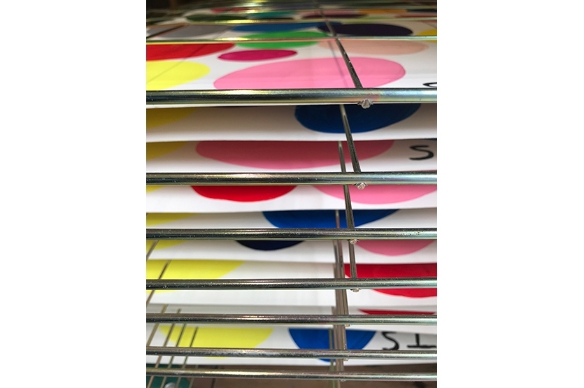 The wet acrylic paintings dry on a drying rack